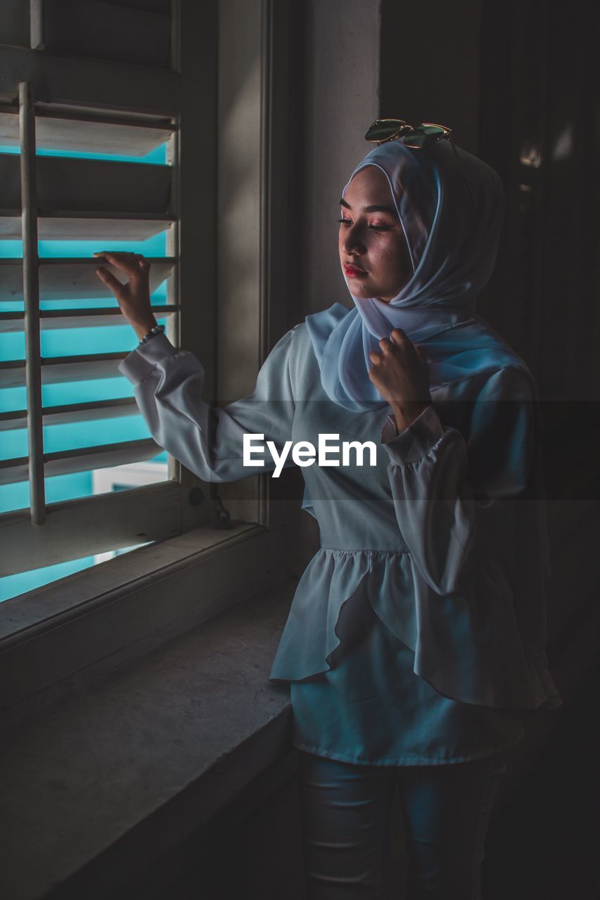 Woman wearing hijab while looking through window