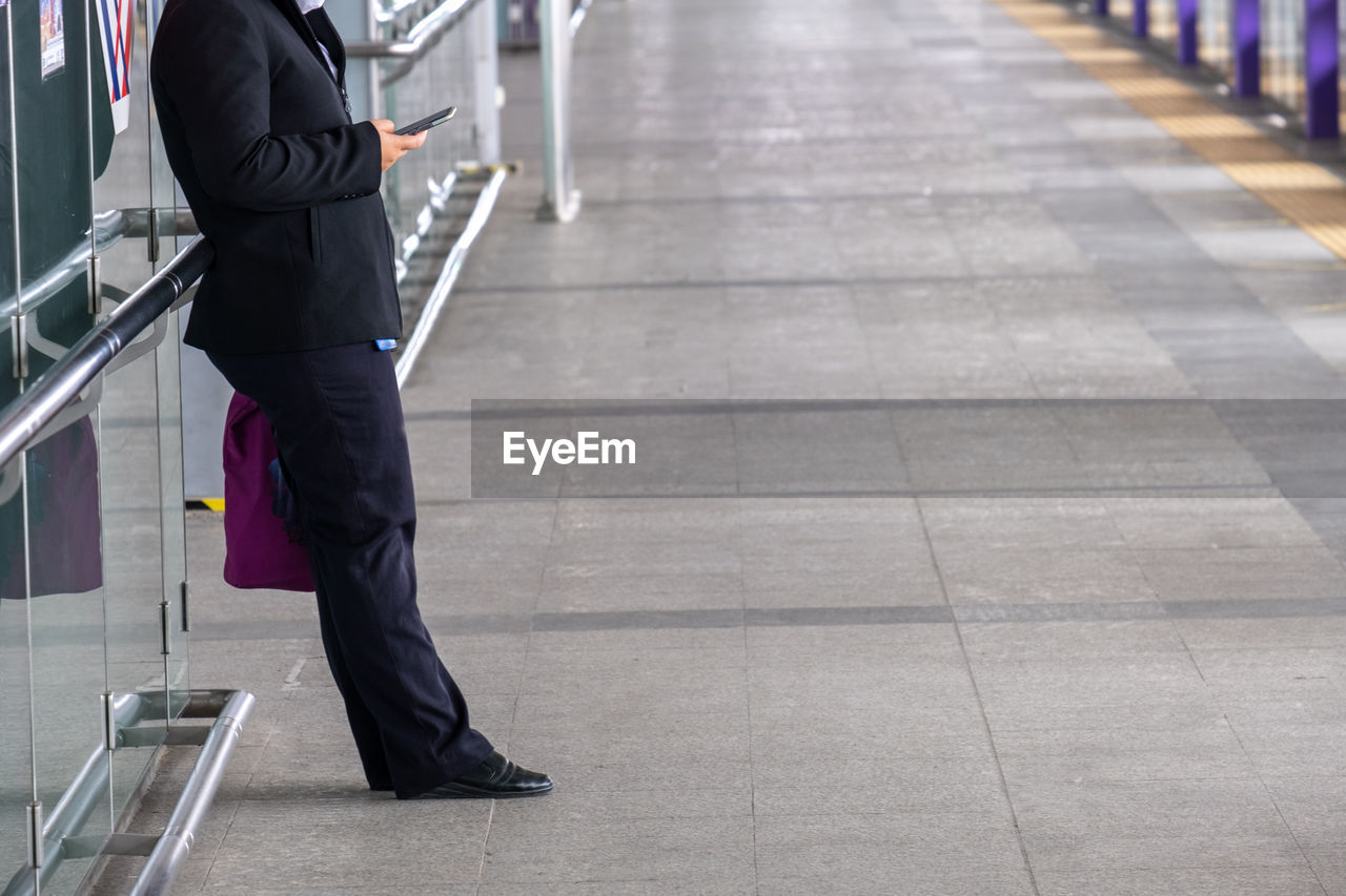 Low section of man using phone at airport