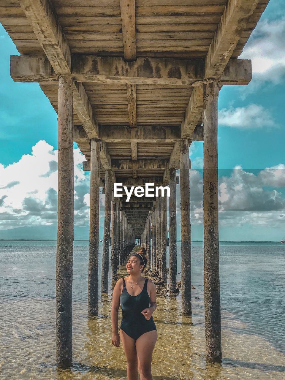 Woman in swimsuit standing under bridge