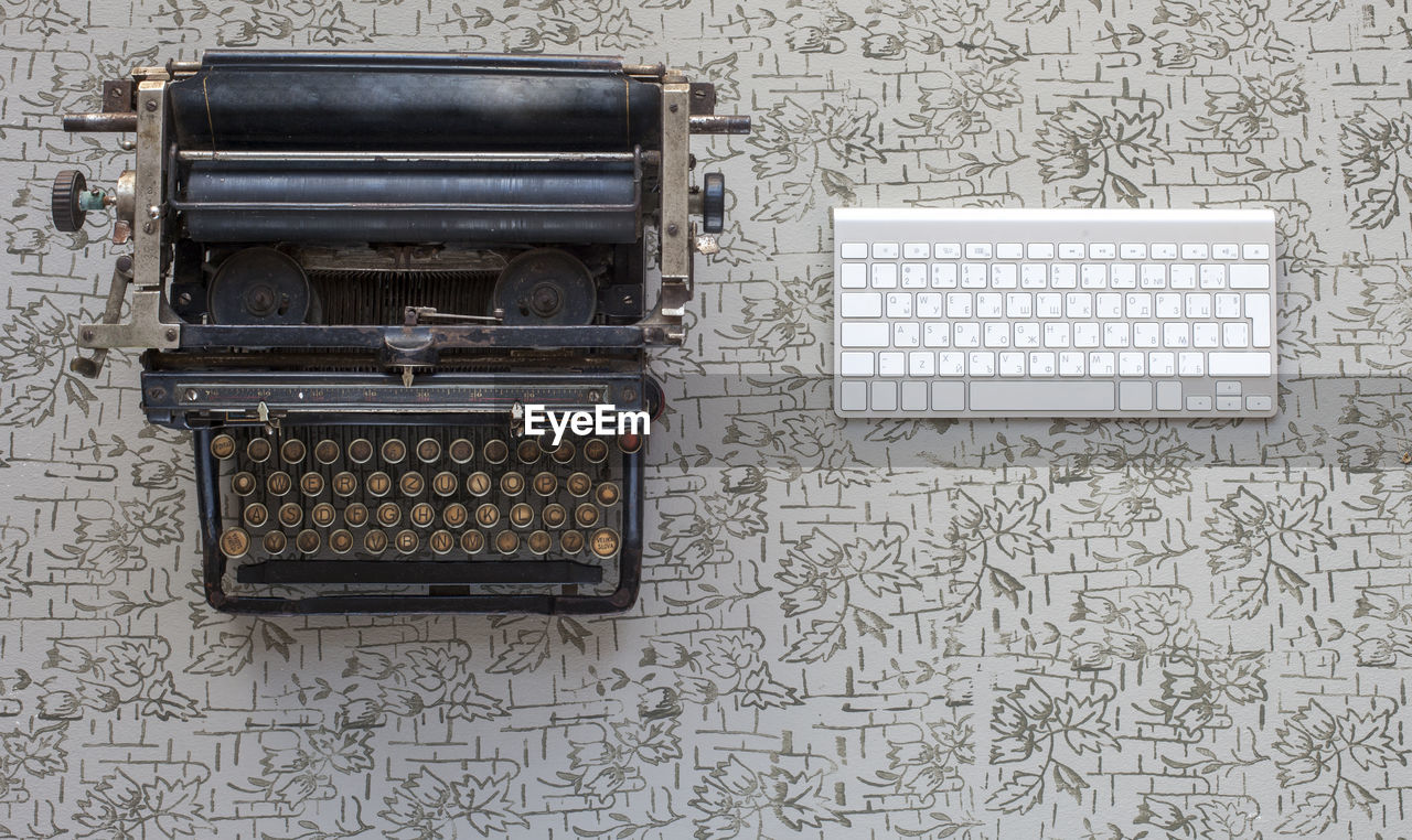 Directly above shot of old typewriter by computer keyboard on table