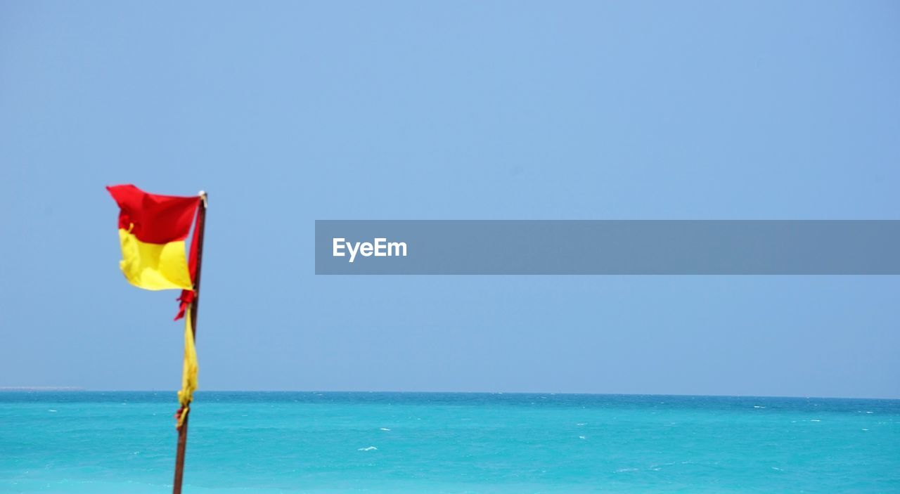 Signal flag at beach by sky and sea