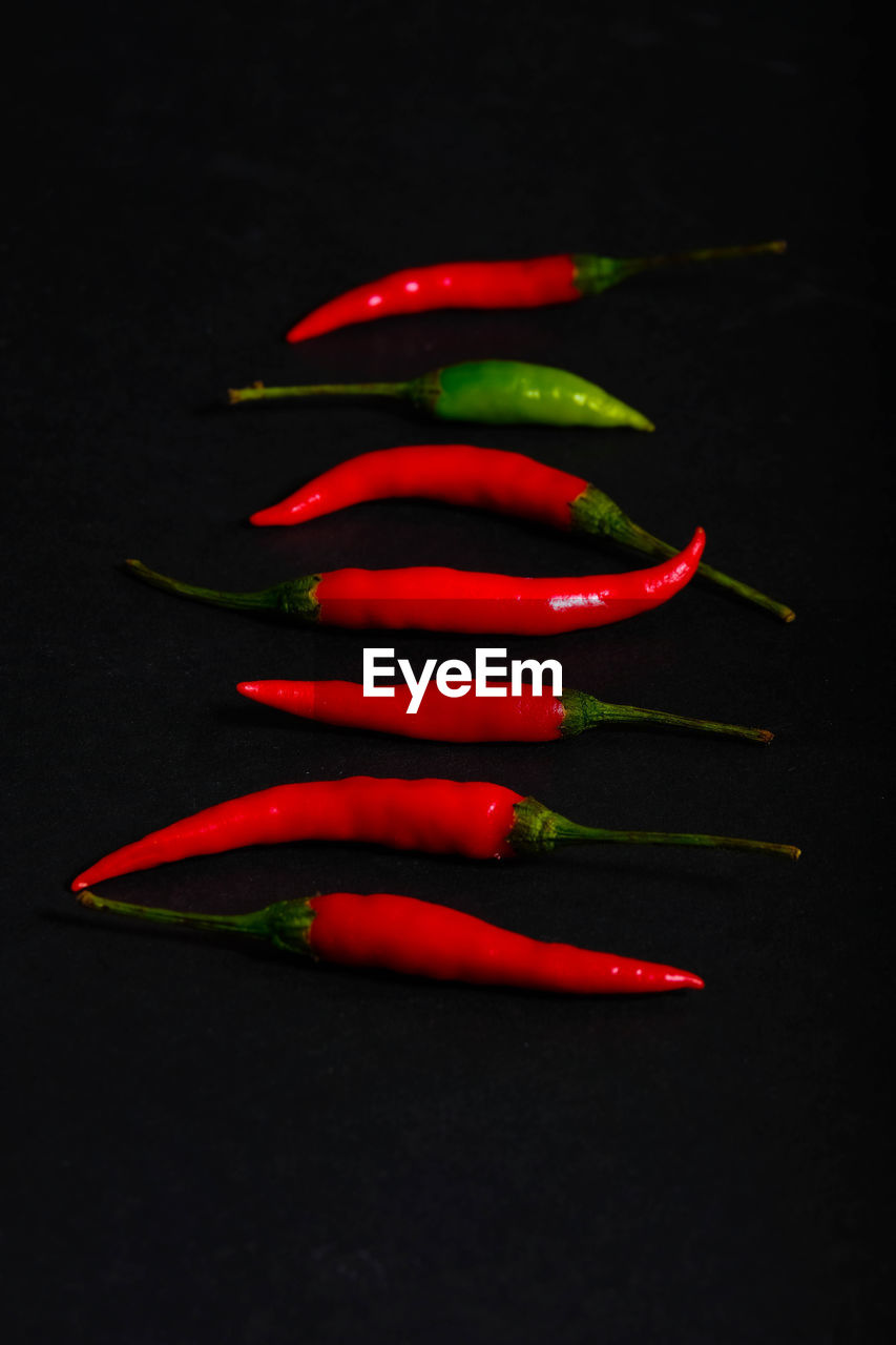 CLOSE-UP OF RED CHILI PEPPER ON BLACK BACKGROUND