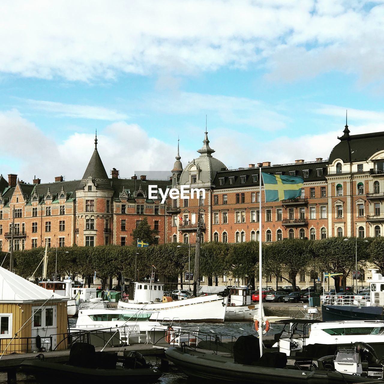 SAILBOATS MOORED ON CANAL BY BUILDINGS AGAINST SKY IN CITY