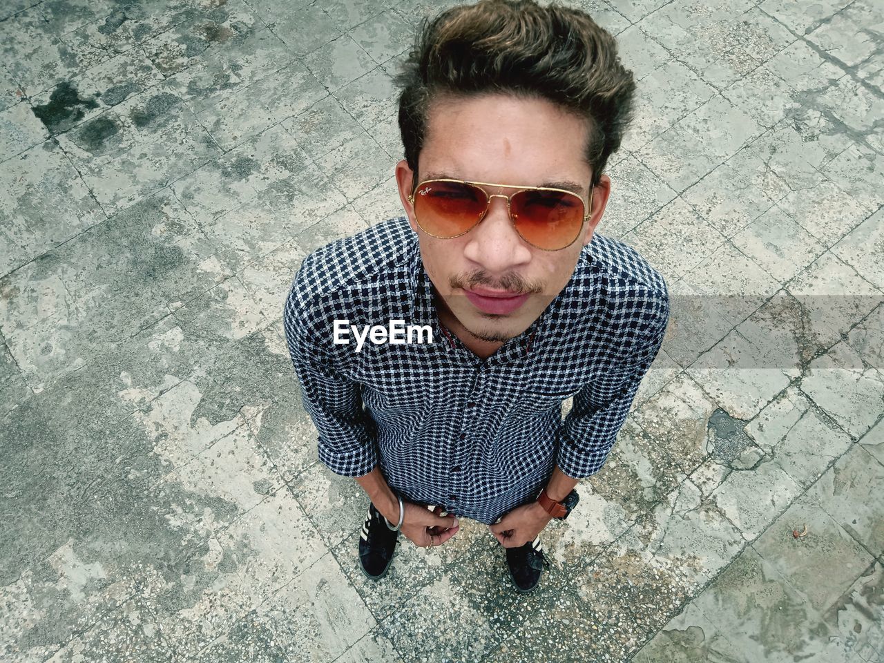 Portrait of young man wearing sunglasses standing on floor