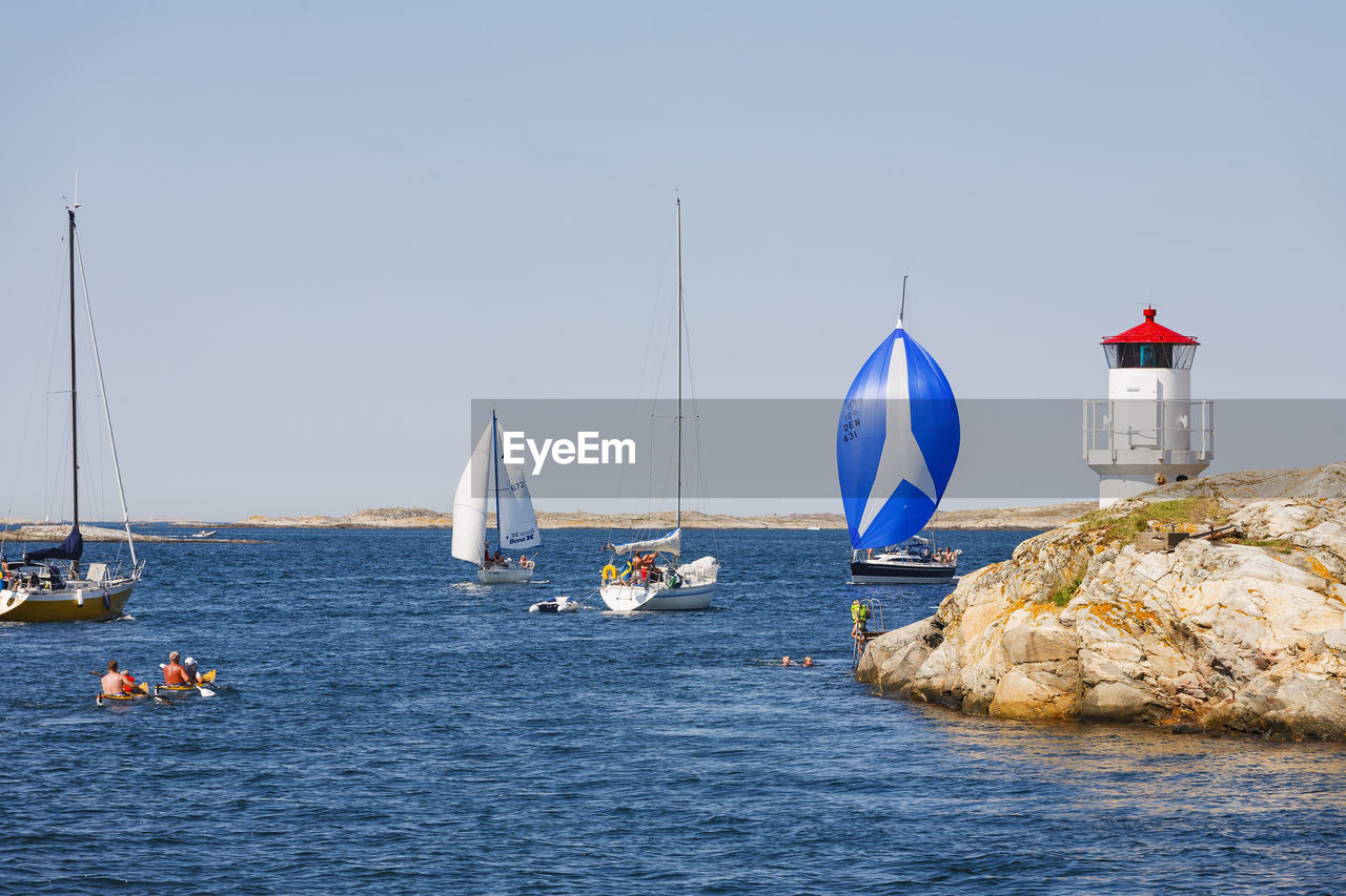 Sailboats and kayaks in a rocky archipelago by a lighthouse