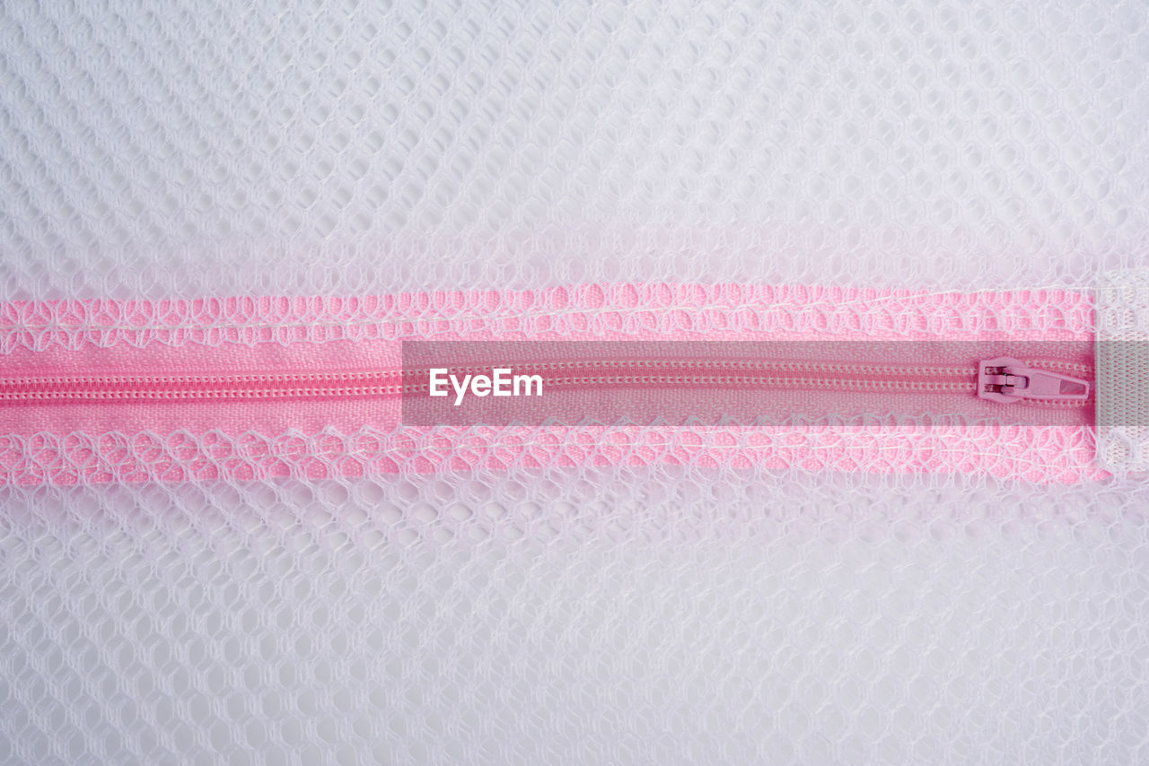 Pink plastic zipper on the laundry bag, full frame, close up