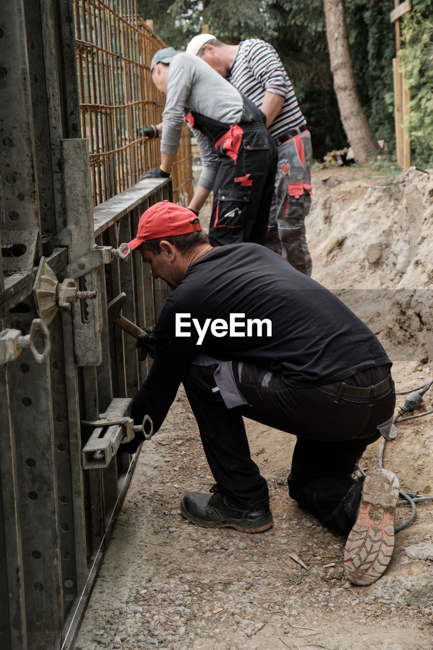 Builder with hammer man carpenter building wall, male hands with a screwdriver close-up. work with