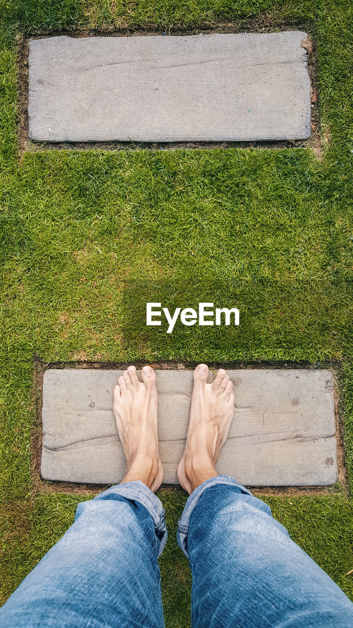 LOW SECTION OF MAN STANDING ON GREEN FLOOR