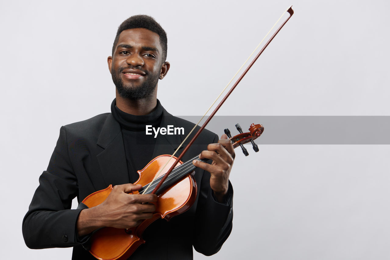 midsection of man playing violin while standing against white background