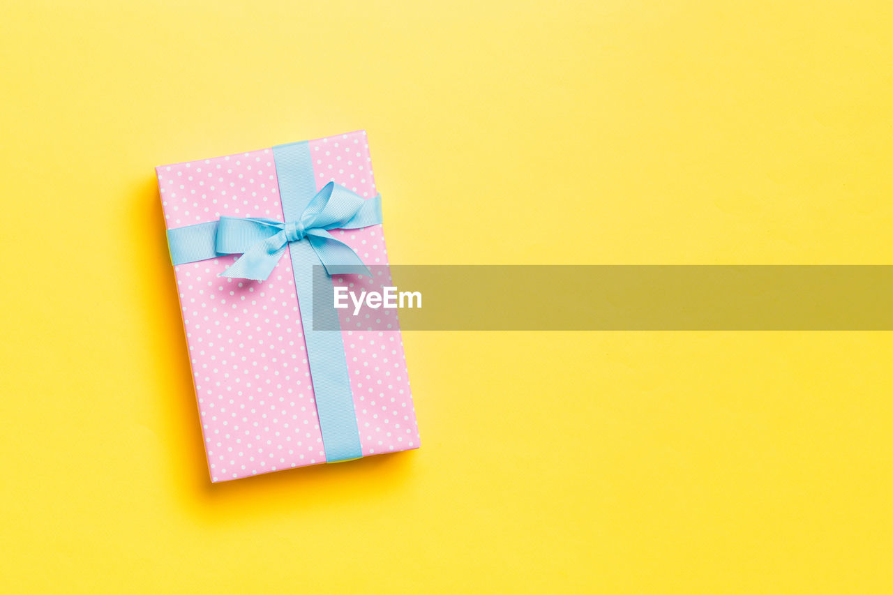 Holiday handmade present in paper on colorful background. present box on colored table, top view.