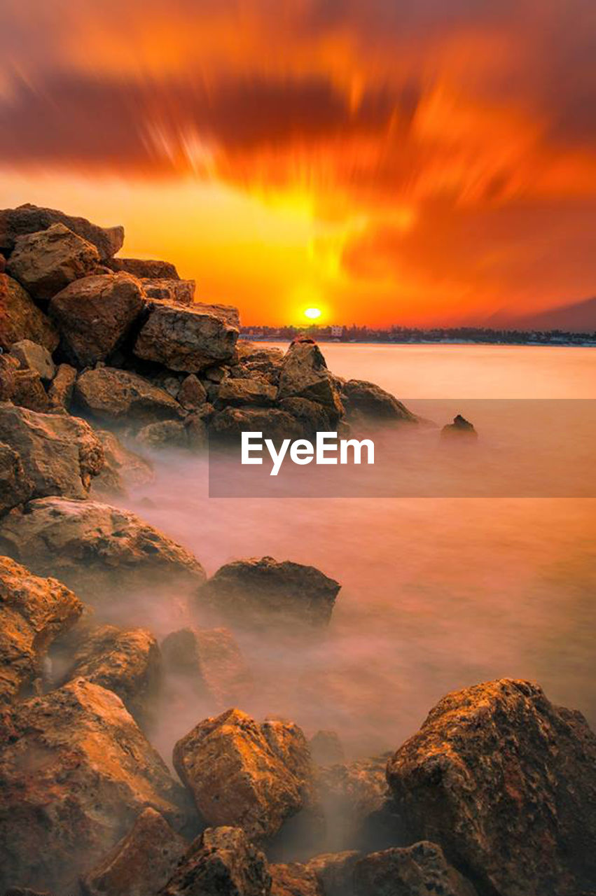 Scenic view of sea against dramatic sky during sunset