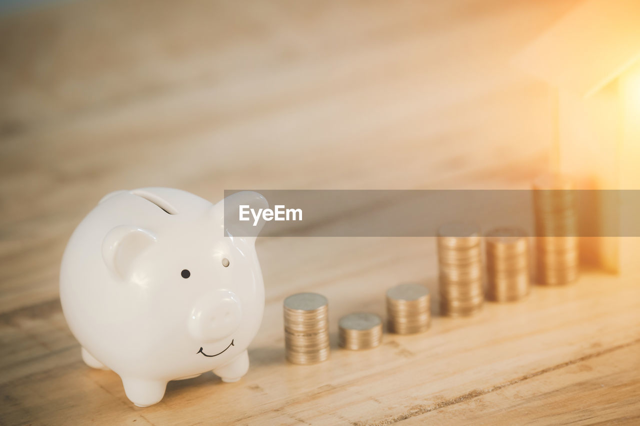 Close-up of coins and piggy bank on table