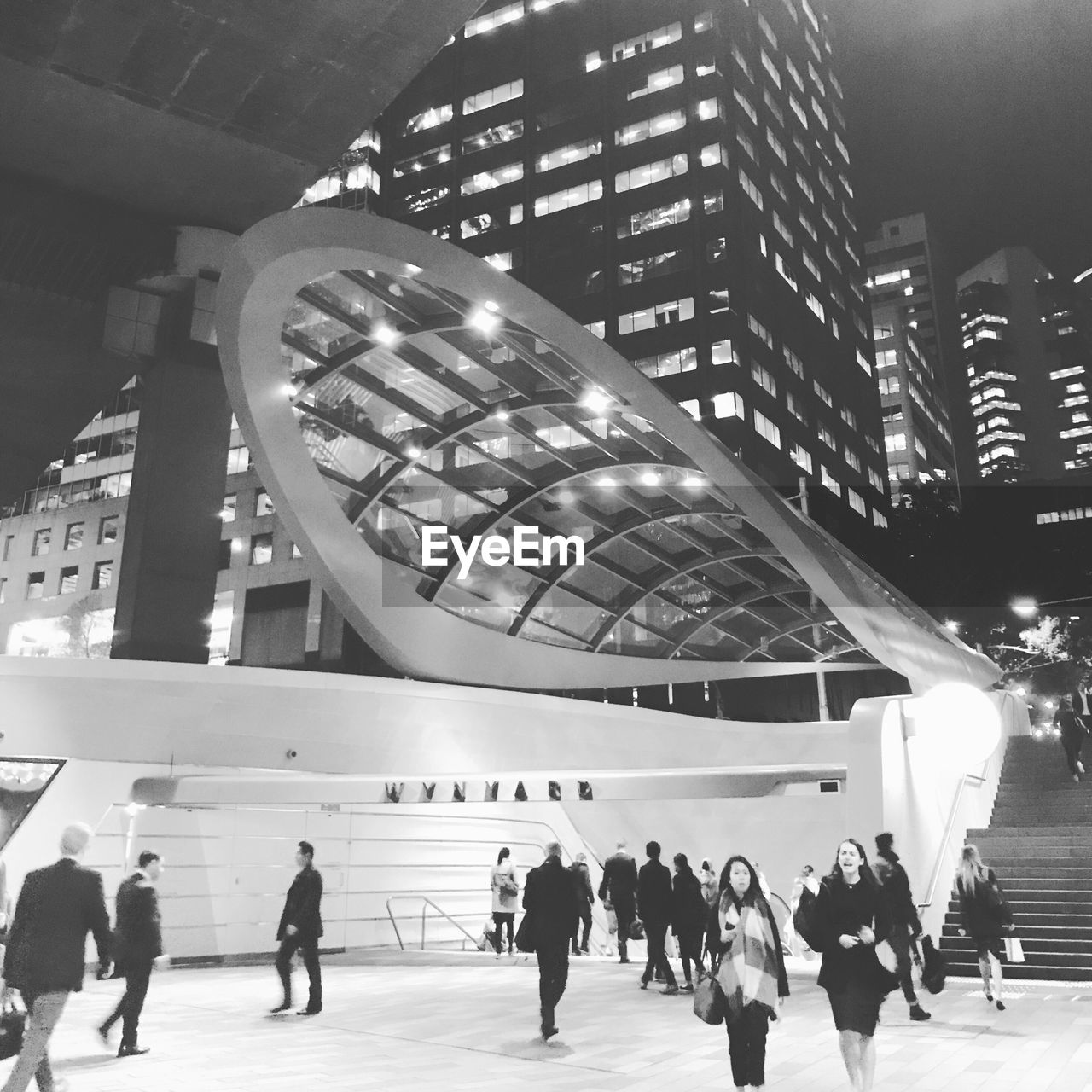 PEOPLE WALKING IN ILLUMINATED MODERN OFFICE BUILDING