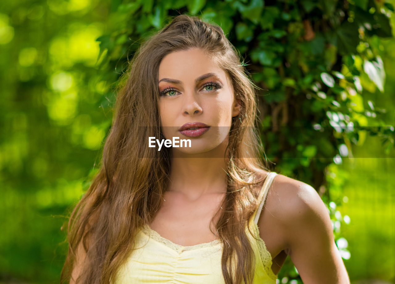 PORTRAIT OF A BEAUTIFUL YOUNG WOMAN AGAINST TREES