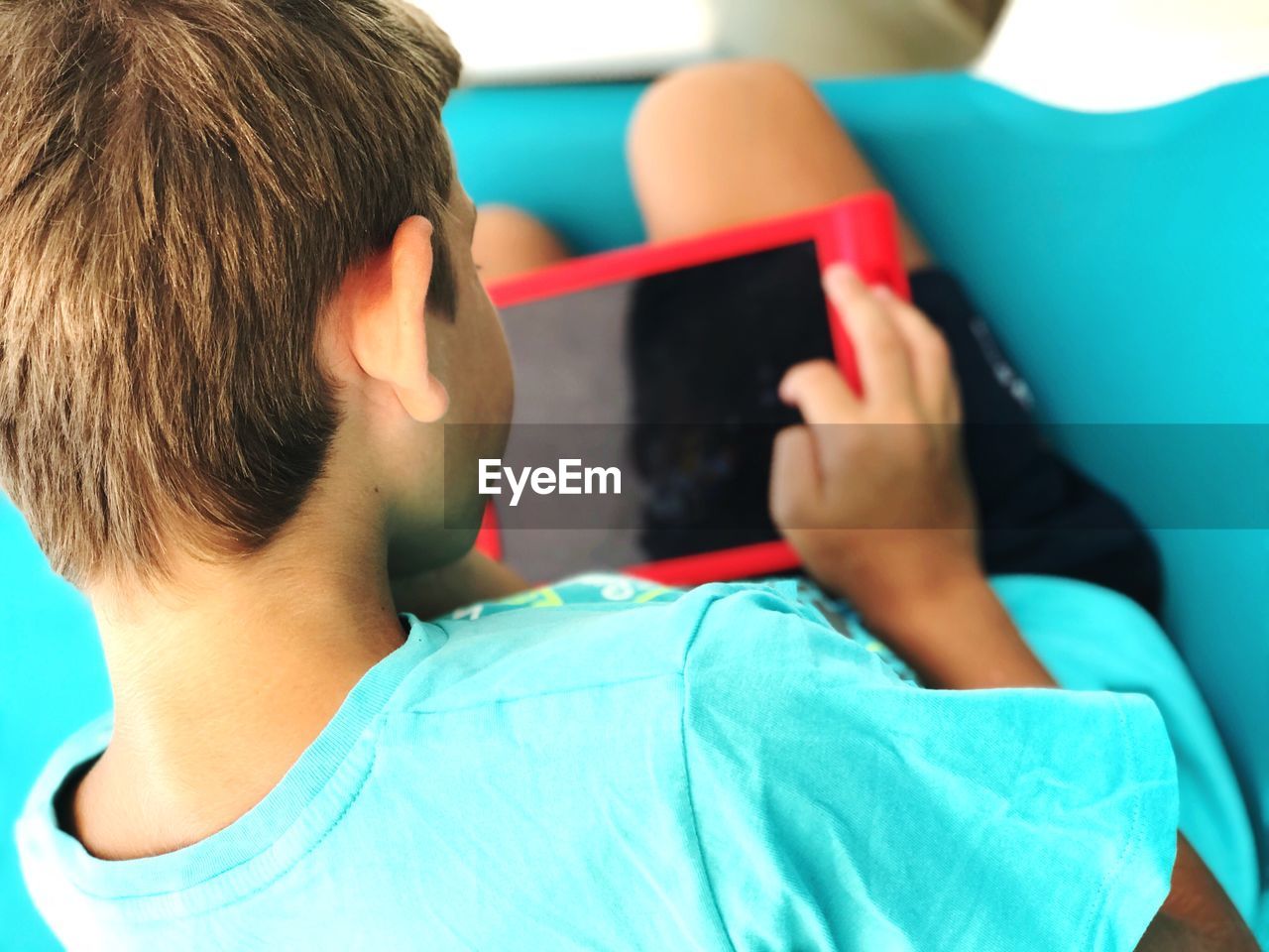 Boy using digital tablet while sitting on sofa