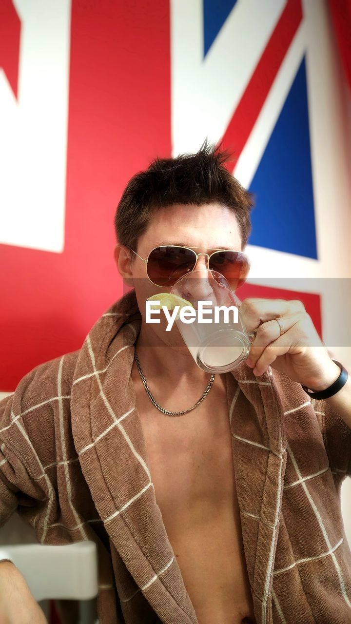 PORTRAIT OF YOUNG MAN DRINKING GLASSES