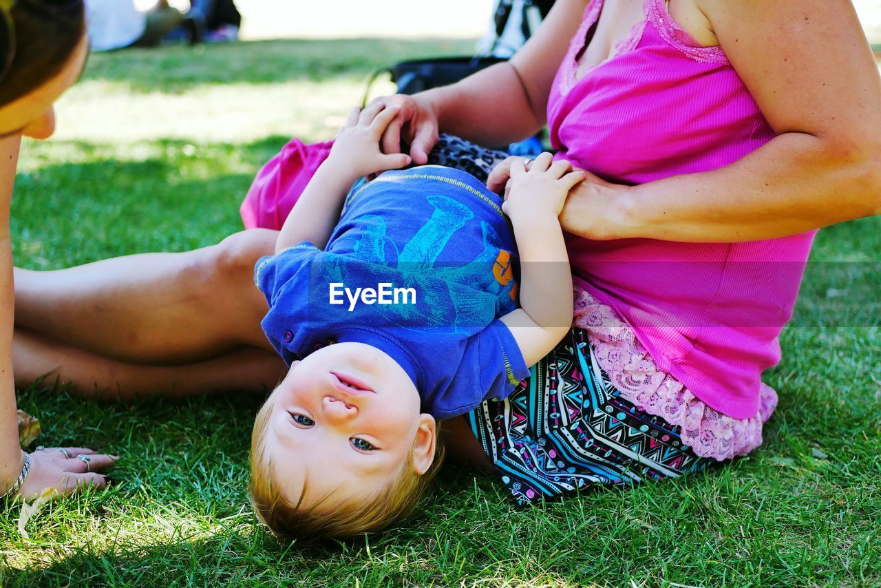 Cheerful mother and son playing on field