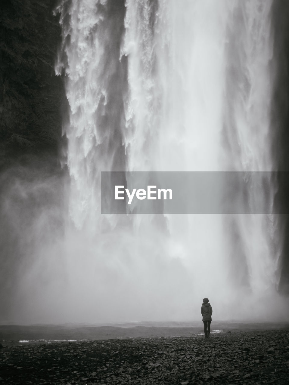 Rear view of person standing against skogafoss waterfall