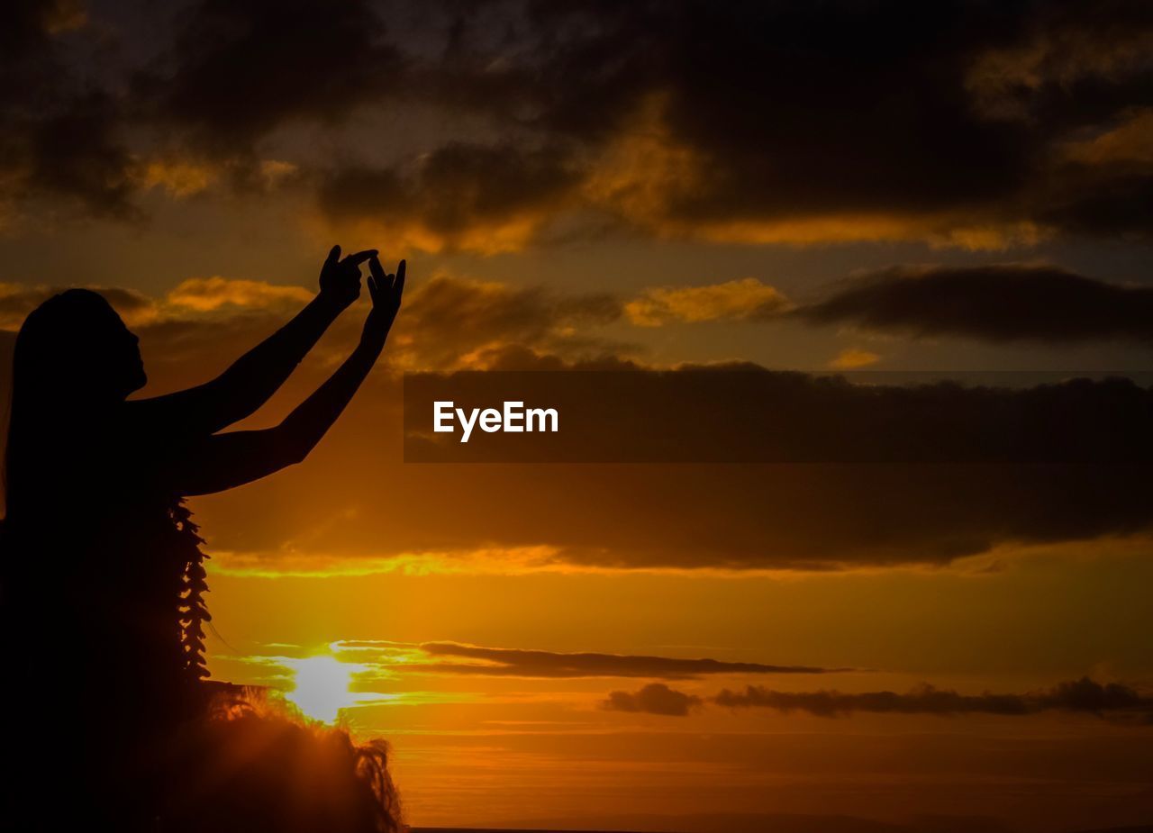 SILHOUETTE WOMAN AGAINST ORANGE SUNSET SKY