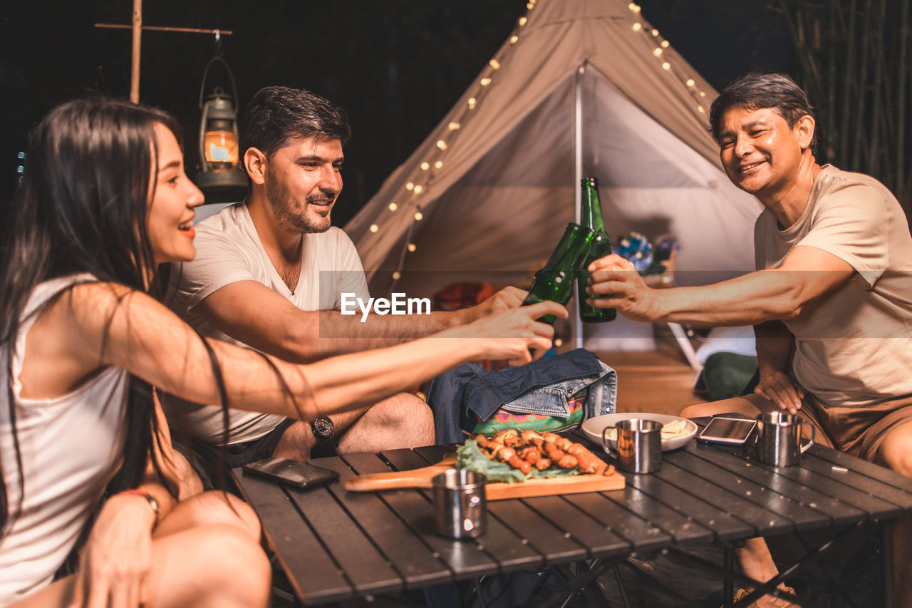 GROUP OF PEOPLE HAVING FOOD AT NIGHT