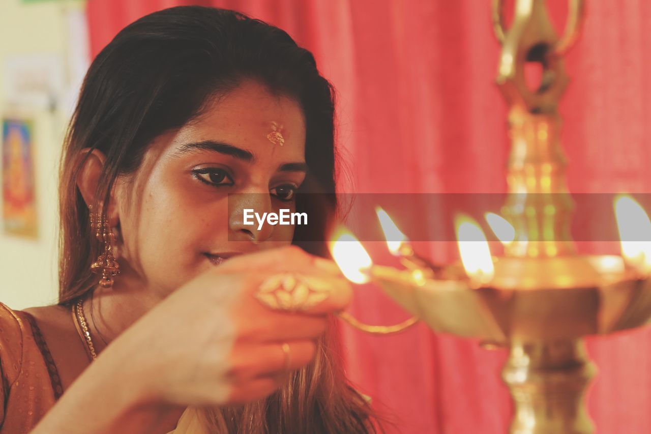 Young woman lighting diya at home