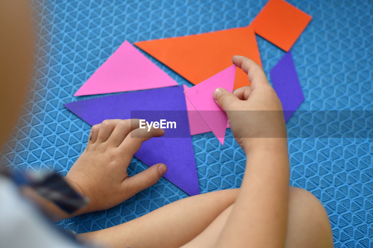 LOW SECTION OF WOMAN PLAYING WITH MULTI COLORED PAPER