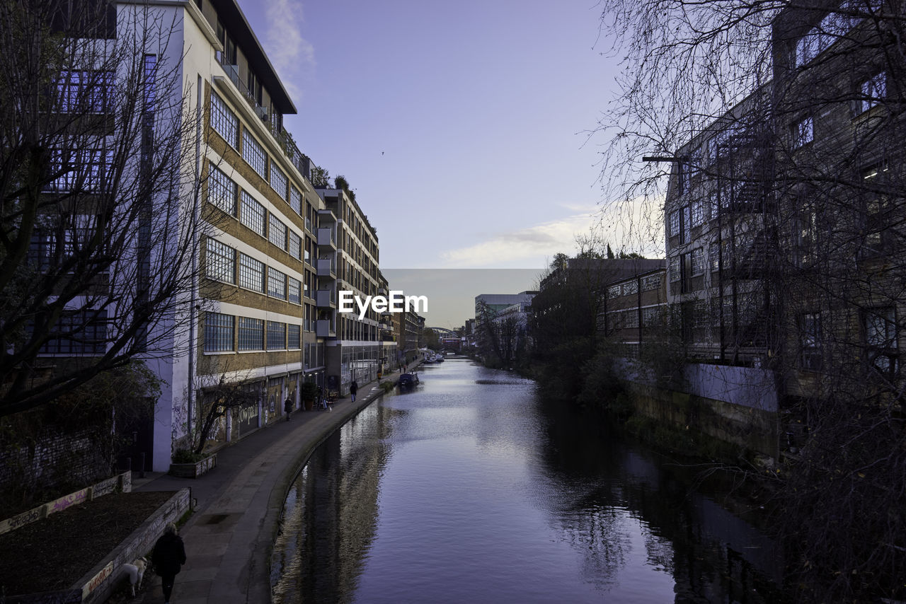 Canal amidst buildings in city against sky