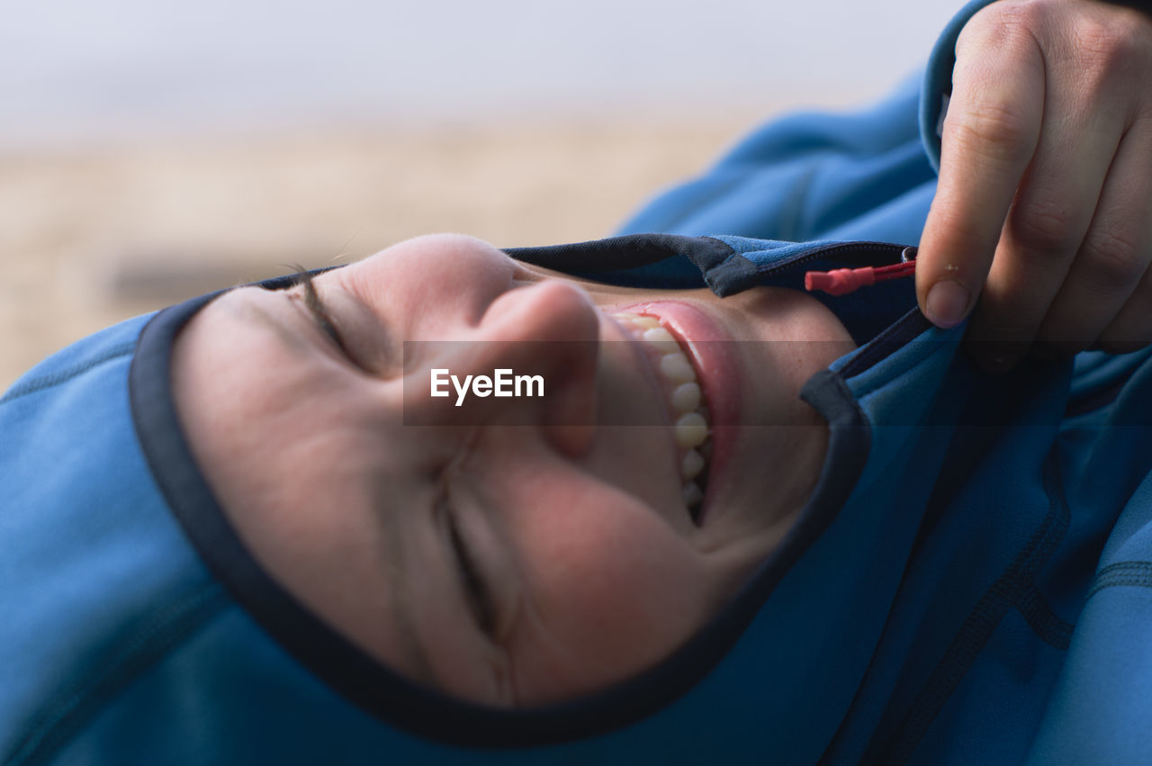 Portrait of a laughing woman in hooded fleece jacke by the shore. close-up