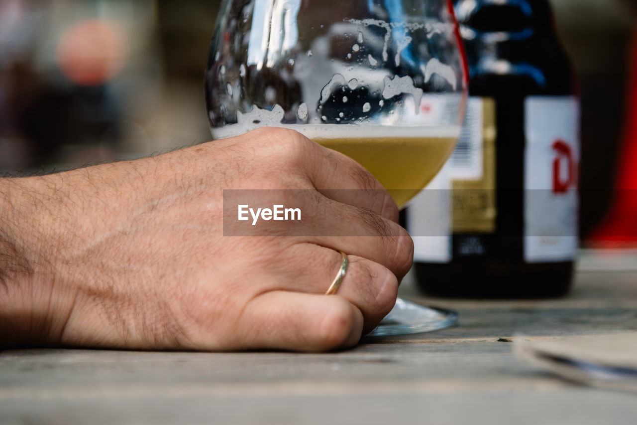 Cropped image of hand holding beer glass on table