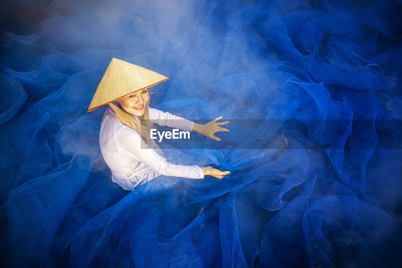Portrait of smiling woman sitting on blue fishing net