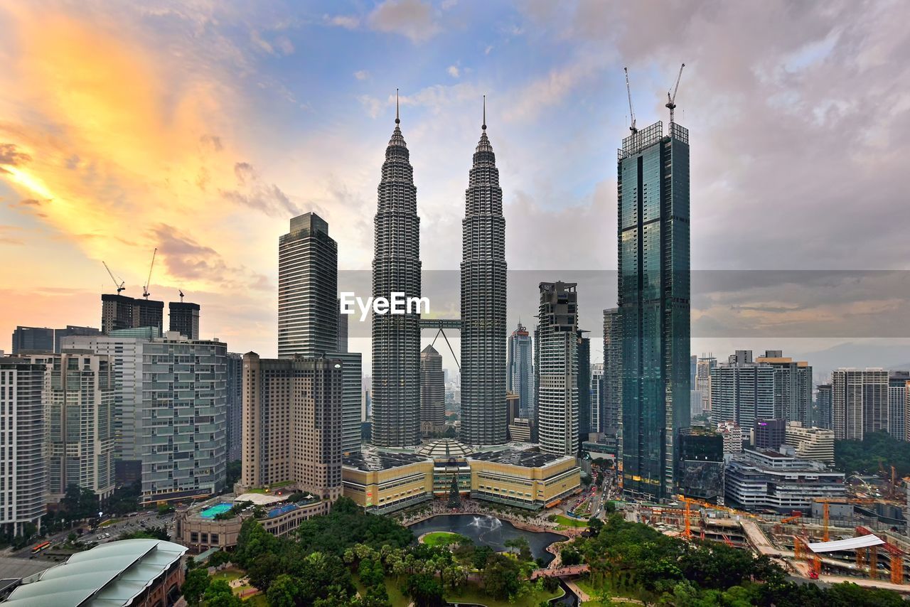 Modern buildings in city against sky during sunset