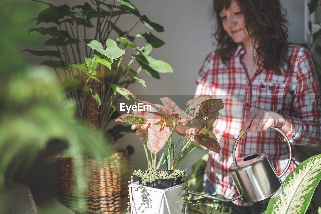 portrait of young woman standing by potted plant