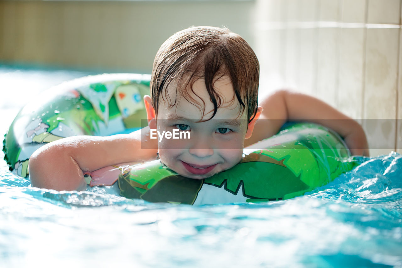 Portrait of happy boy swimming with inflatable ring in pool