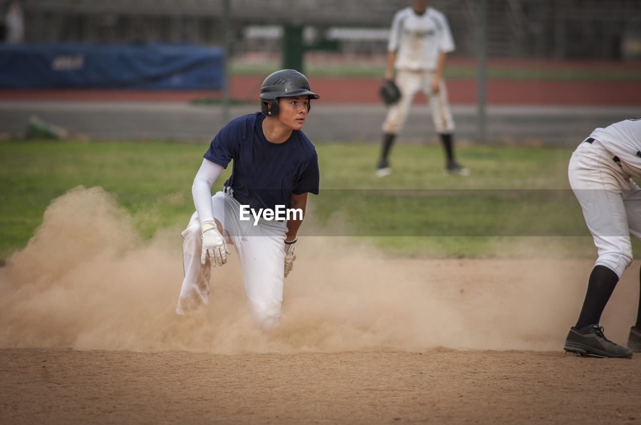 Young baseball player in cloud of dust after sliding into second base