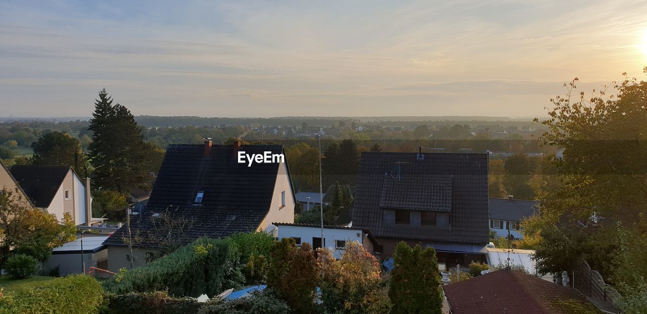 HIGH ANGLE VIEW OF HOUSES AND TREES AGAINST SKY