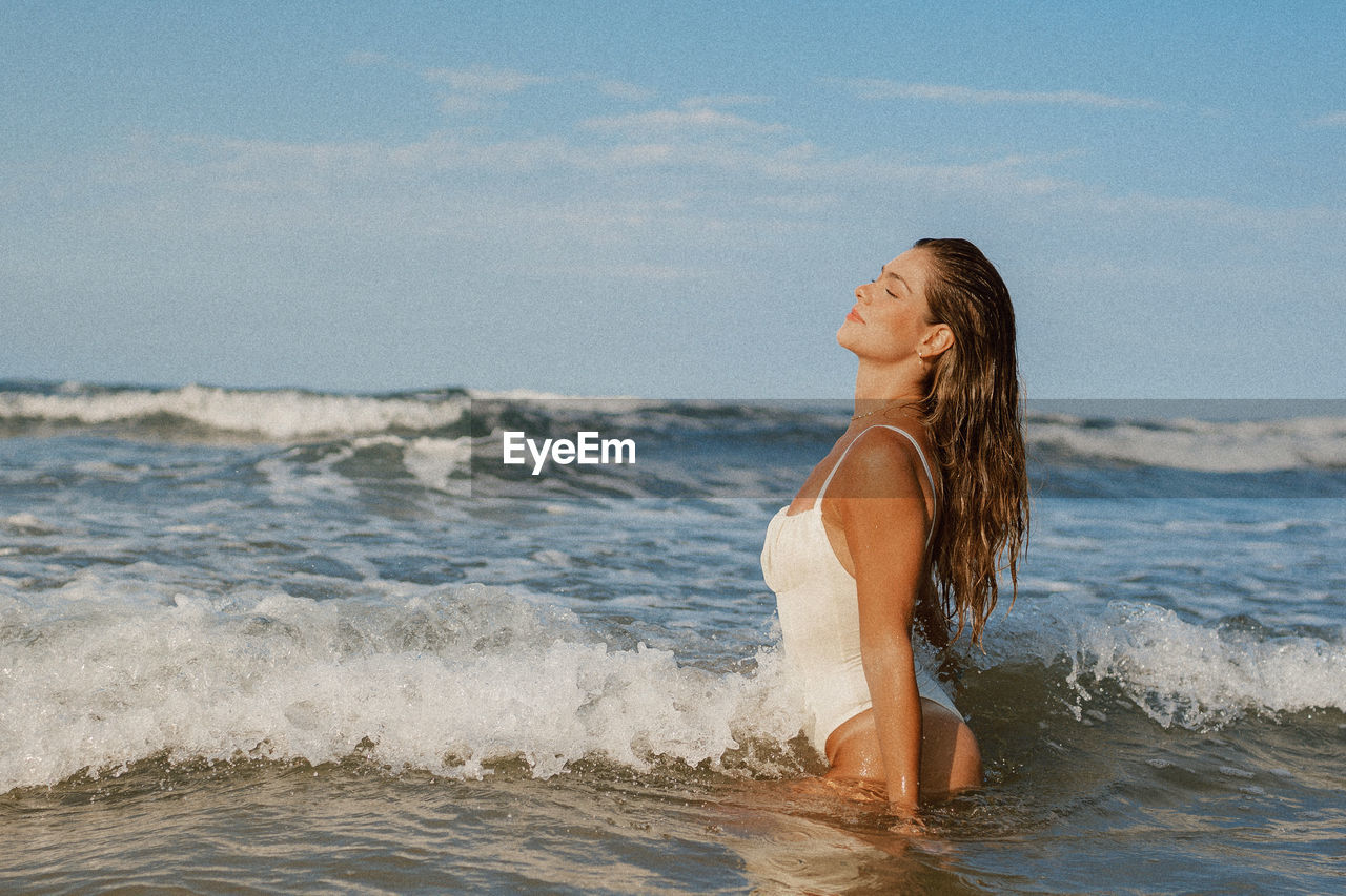 Portrait of young woman standing at beach