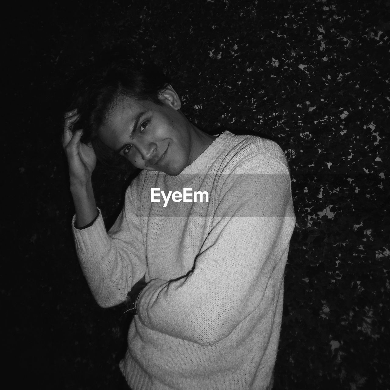 Portrait of smiling man standing against plants at night