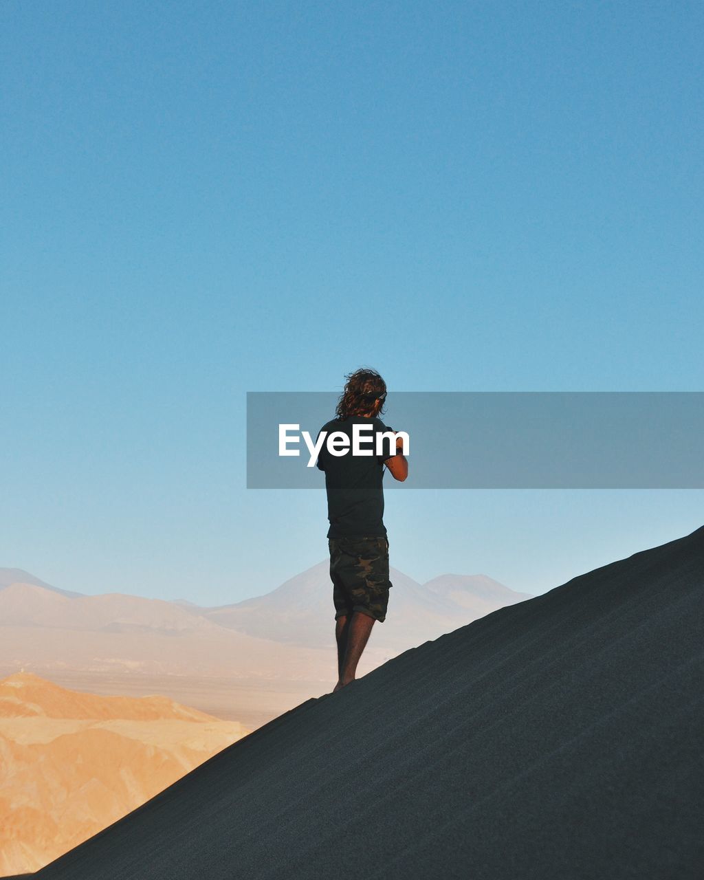 Rear view of person standing on mountain against clear sky