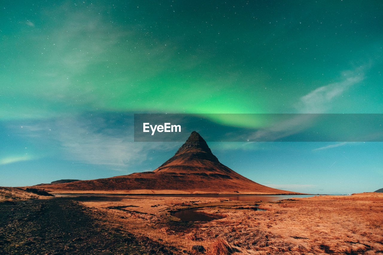 Scenic view of arid landscape against aurora borealis