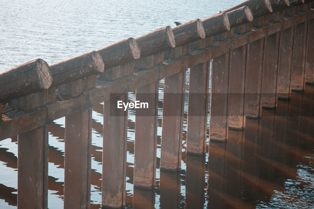 HIGH ANGLE VIEW OF WOODEN POSTS IN SEA