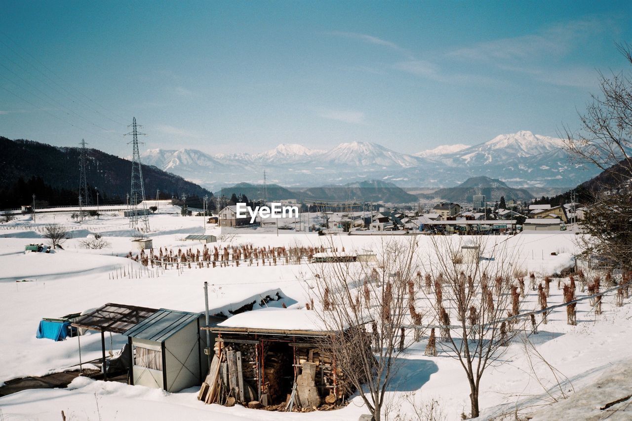 View of houses on snowcapped landscape with mountains in background against sky