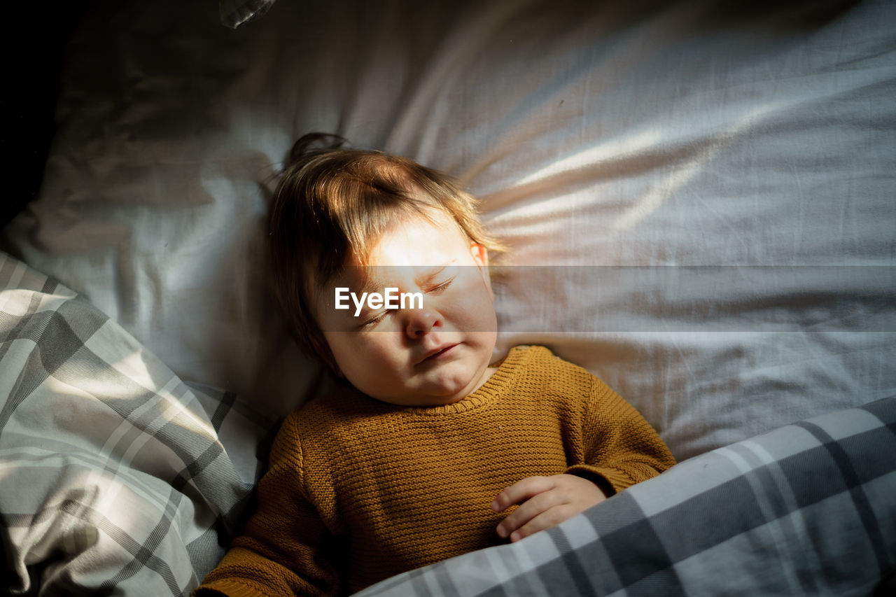 Directly above shot of cute baby boy lying on bed at home