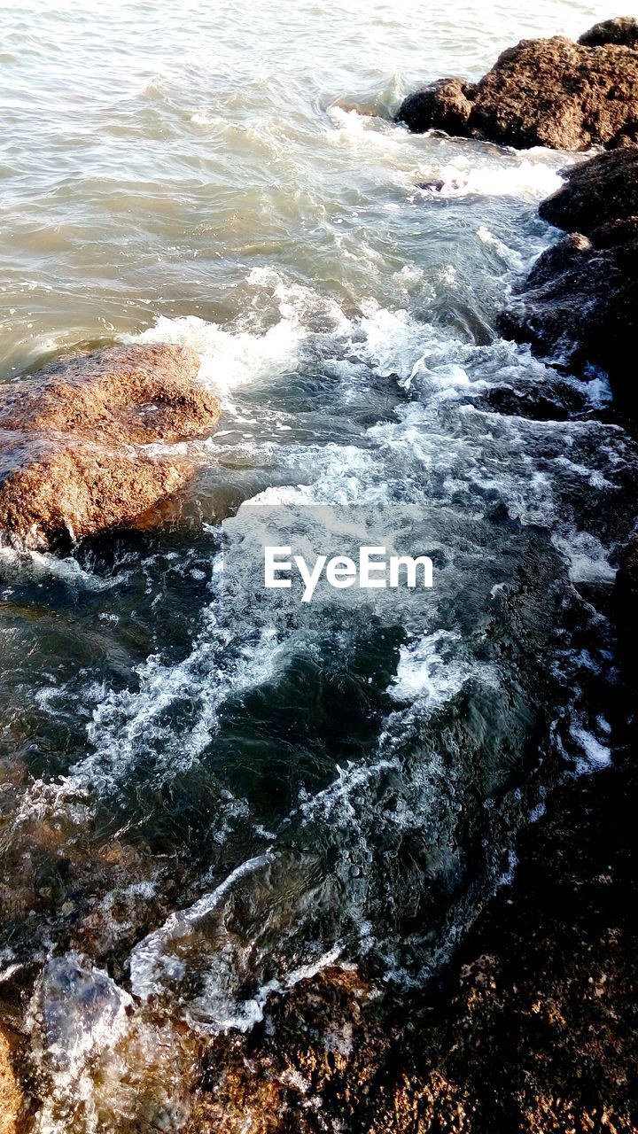 HIGH ANGLE VIEW OF WAVES SPLASHING ON ROCKS