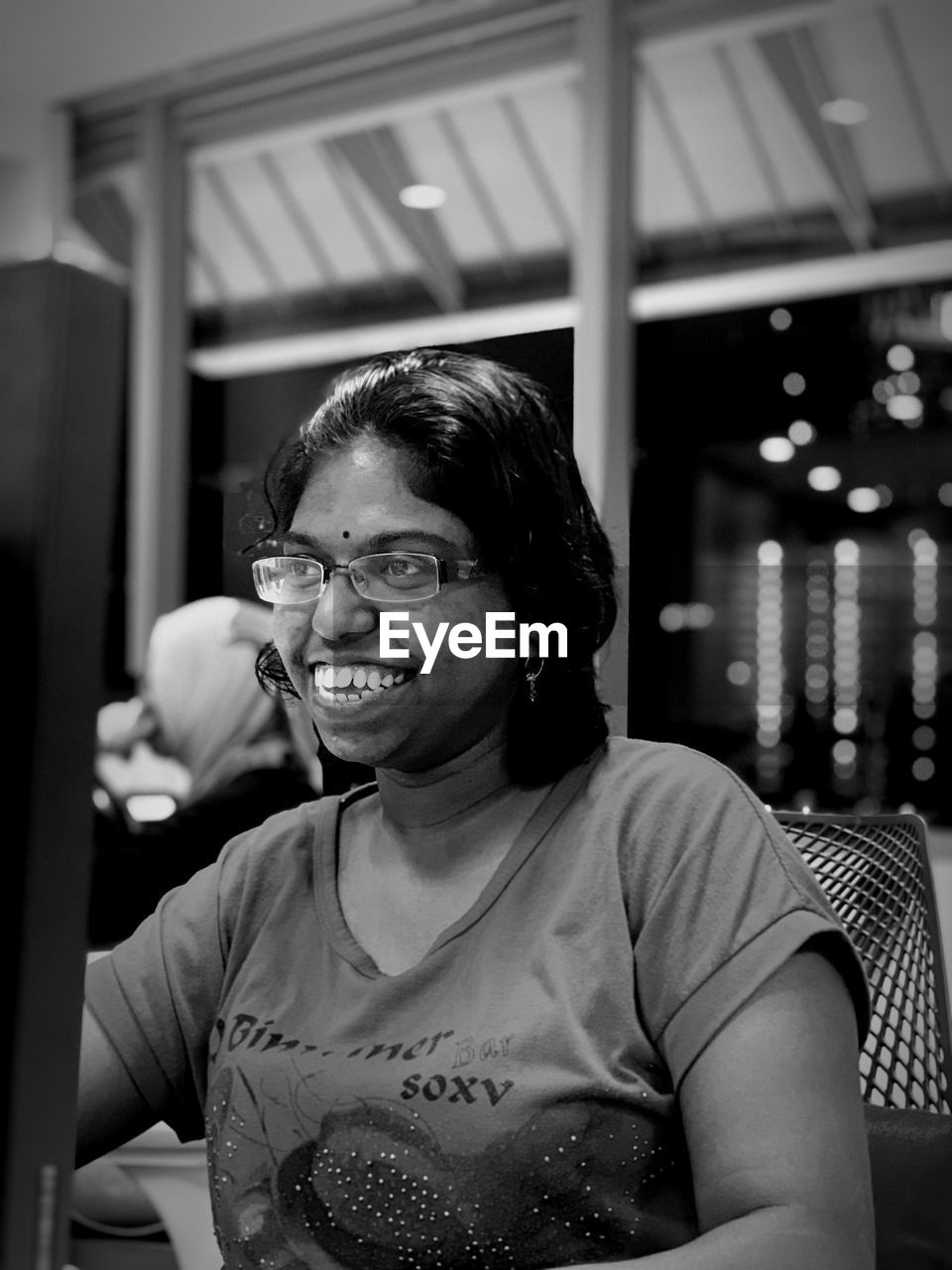 Smiling woman wearing eyeglasses looking away while sitting on chair