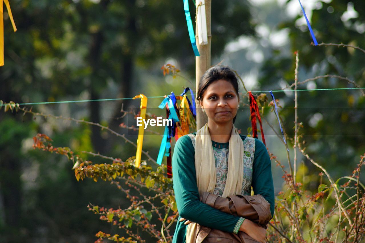 Portrait of young woman standing against plants