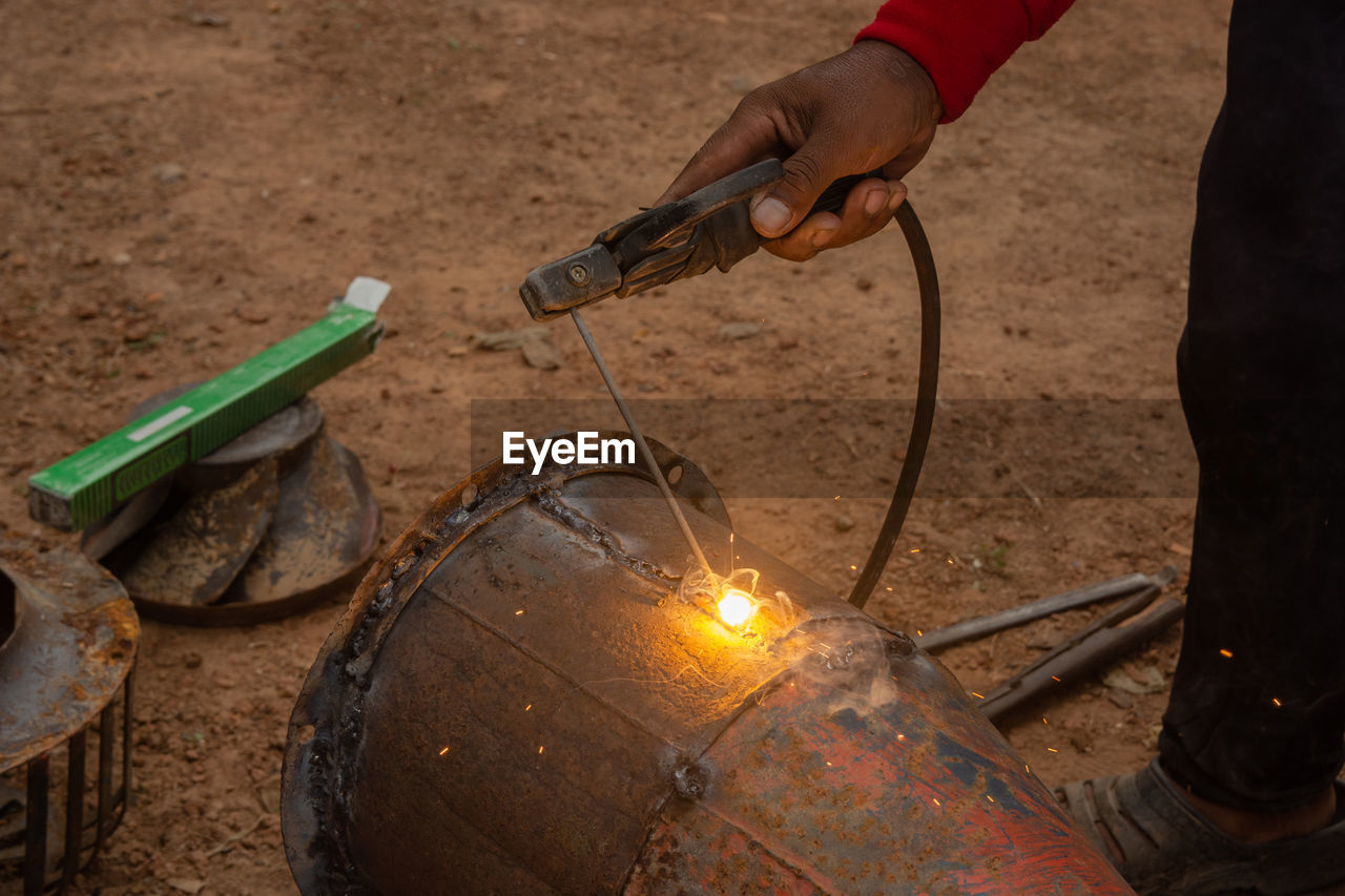 Low section of man working on metal