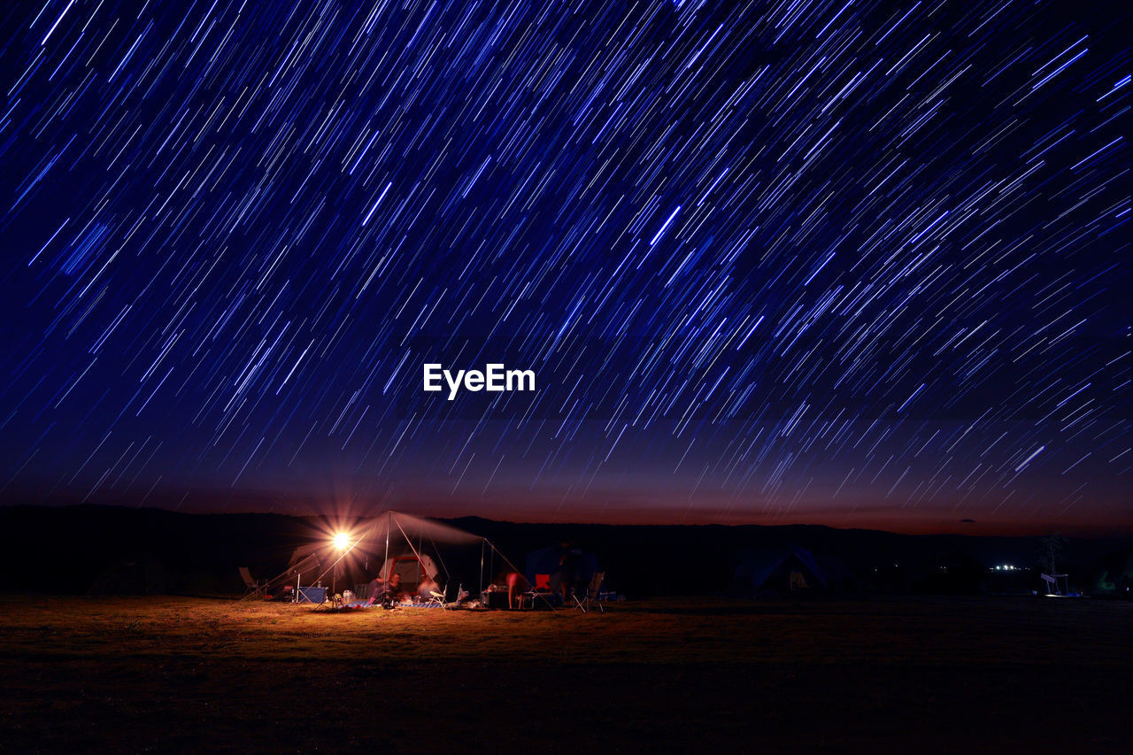 Scenic view of star trails over field at night