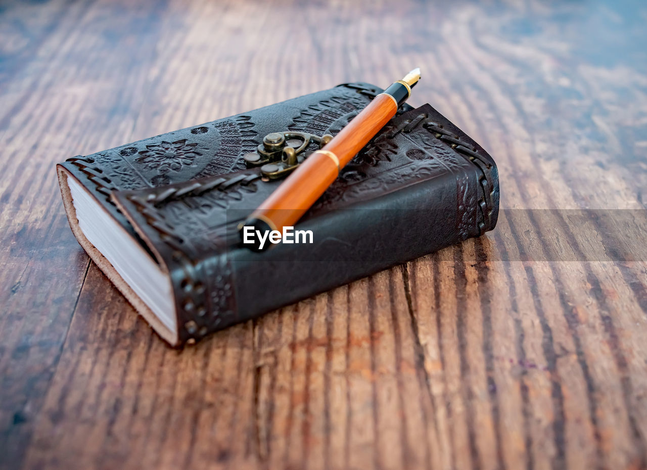 14 selective focus of wooden fountain pen on top of a leather bound note book