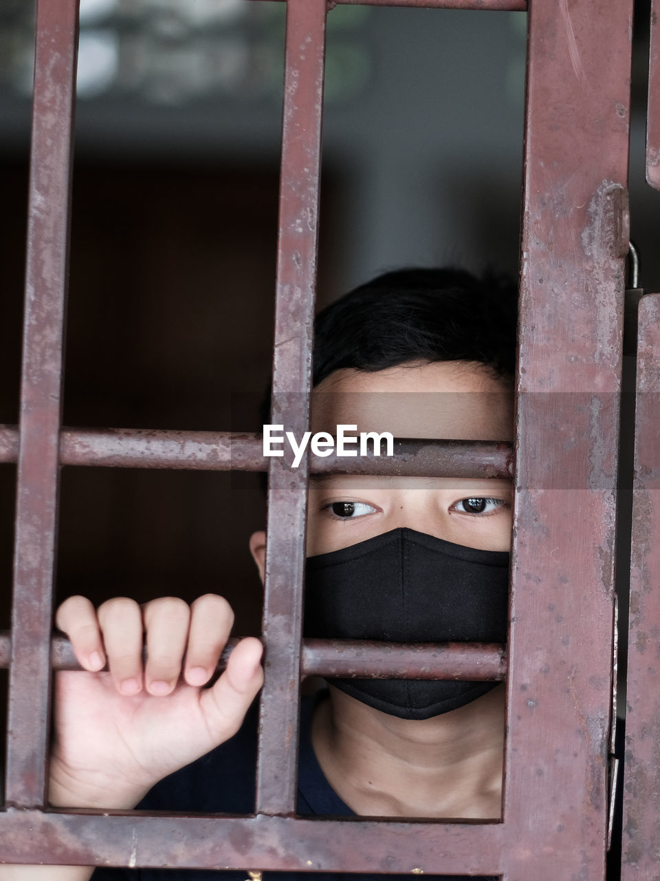 Portrait of a boy with face mask stuck indoors