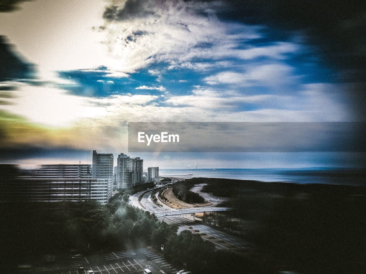 View of cityscape and highway against cloudy sky